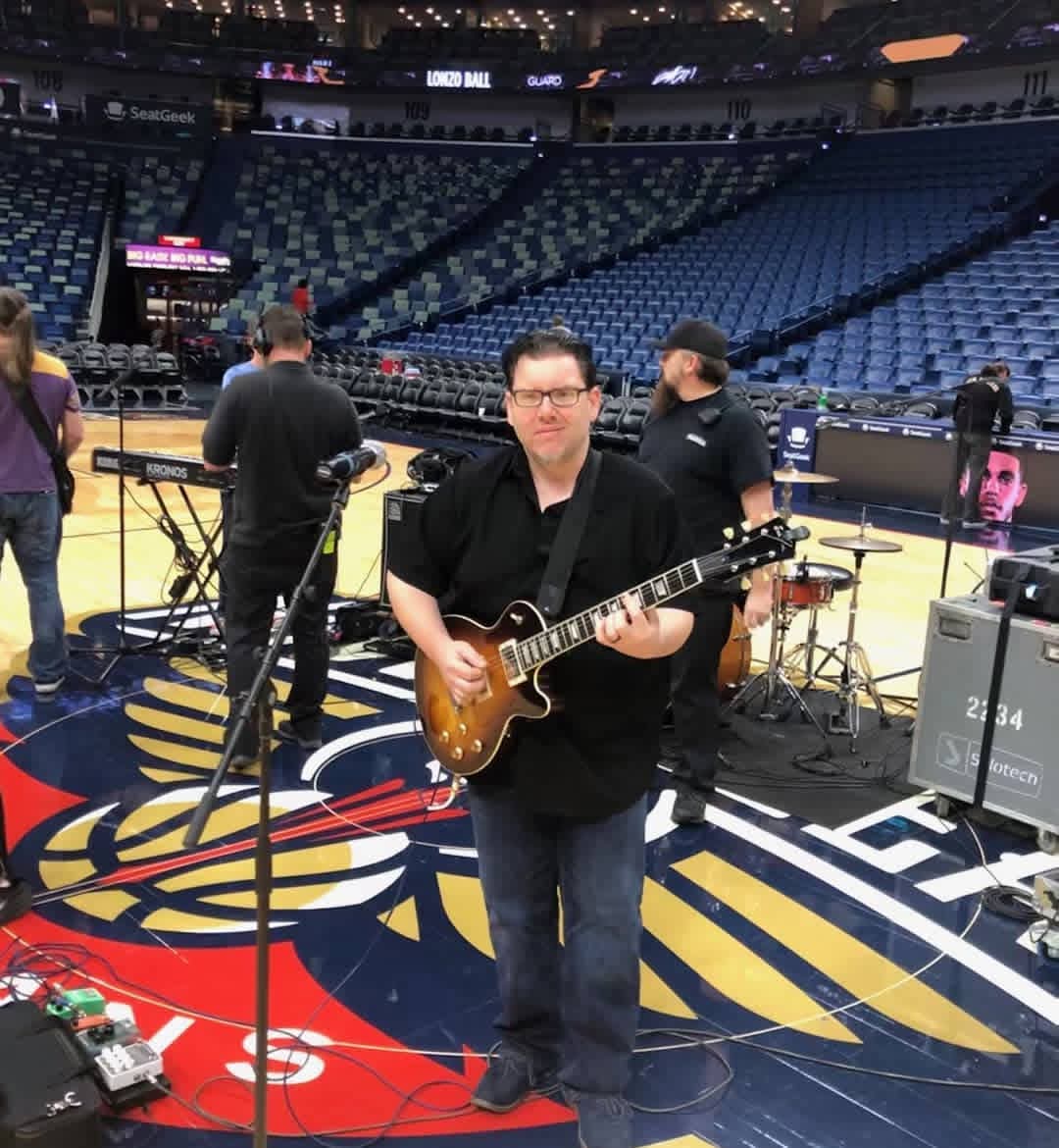 Jack Miele playing a sunburst Les Paul on a basketball court during an arena soundcheck